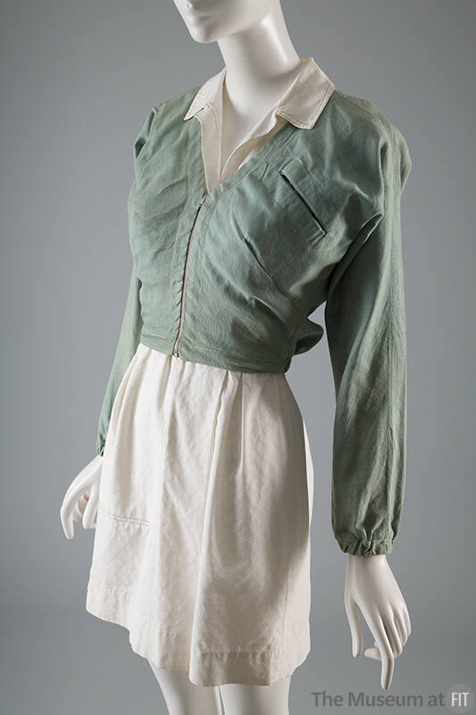 Cropped pale denim V-neck, zippered jacket with cinched sleeves at wrist styled over a  white m…