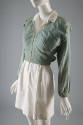 Cropped pale denim V-neck, zippered jacket with cinched sleeves at wrist styled over a  white m…