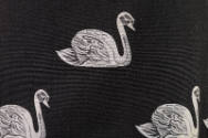 Detail view of black tunic showing white jacquard swans with grey shading details 
