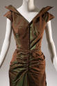 Detail view of brown/green evening dress bodice with pointed cap sleeves and deep V-neck collar…