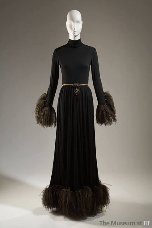 Black floor length evening dress with turtleneck, black ostrich feather trim at wrists and hem …