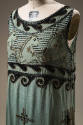 Detail view of turquoise dress bodice showing black and gold beaded horse design and beaded scr…
