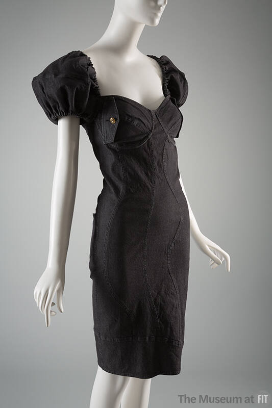 Black denim knee length sheath dress with multiple curved seams, short puffed sleeves and brass…