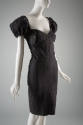 Black denim knee length sheath dress with multiple curved seams, short puffed sleeves and brass…