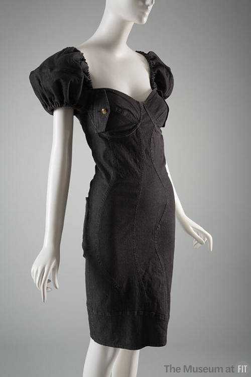 Black denim knee length sheath dress with multiple curved seams, short puffed sleeves and brass…