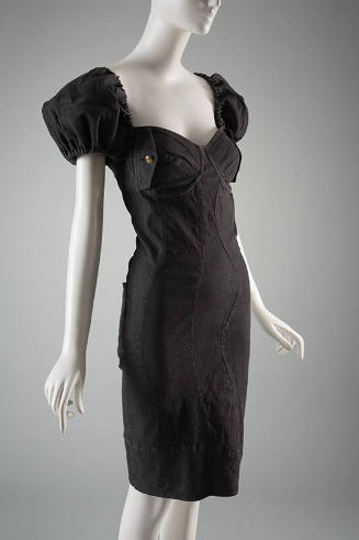 Black denim knee length sheath dress with multiple curved seams, short puffed sleeves and brass…