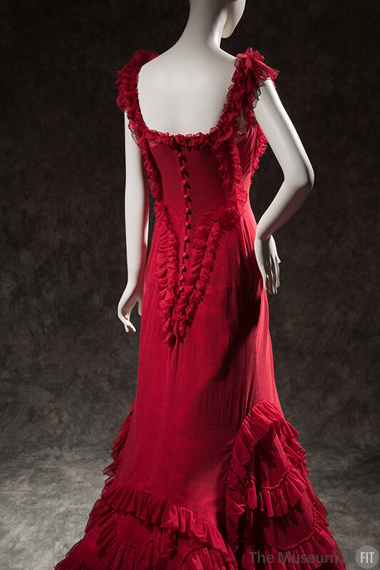 Back view of red sleeveless floor length dress with ruffle trim and button back 