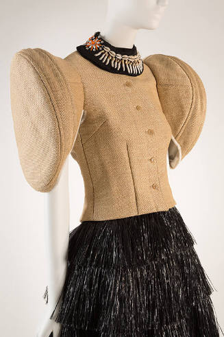 Detail of beige grasscloth button front jacket with stiff round short sleeves, cowrie shell nec…