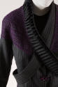 Detail view of grey and black striped pantsuit jacket showing purple applique across shoulders …