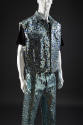 Light blue denim ensemble: sleeveless jacket and jeans covered with large varying blue, silver,…