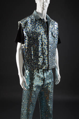 Light blue denim ensemble: sleeveless jacket and jeans covered with large varying blue, silver,…