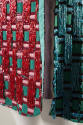 Detail view of aqua green and dark grey striped dress showing beaded panels of pink and red and…