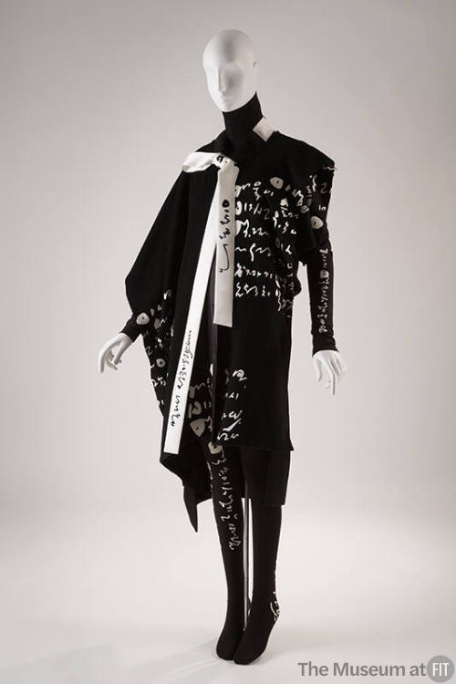 Black sleeveless coat, turtleneck sweater and leggings with white Korean script print throughou…