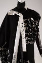 Detail view of black ensemble showing white handwritten Korean script throughout and long white…