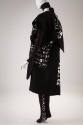 Back view of black ensemble showing white Korean script throughout and sleeveless coat over bla…