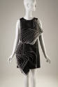 Black sleeveless short dress with stacked square layers outlined in white opening diagonally on…