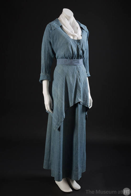 Blue chambray two-piece dress with long sleeve scoop neck bodice, belted waist and asymmetrical…