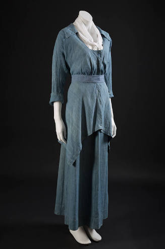 Blue chambray two-piece dress with long sleeve scoop neck bodice, belted waist and asymmetrical…