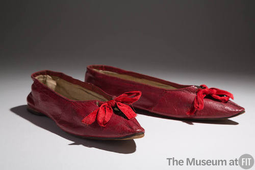 Pair of red leather flat shoes with pointed toe and red ribbon bow tie on vamp 