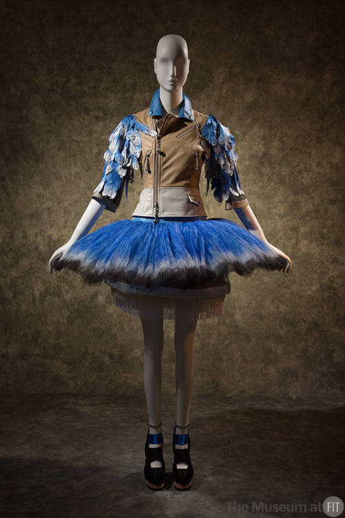 Tan leather motorcycle jacket with blue and white faux feather sleeves, flared blue tutu skirt …