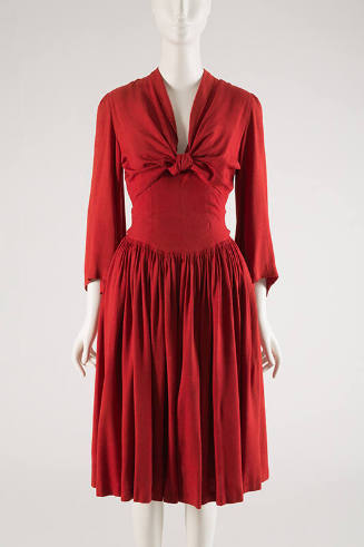 Red knee-length dress with pleated skirt and long bell sleeves and tie panels that knot at cent…