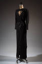 Floor-length black dress with triangular cut out at the bust and black sequin elements
