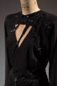 Torso detail of black dress with triangle cut out at bosom with sequined tendrils across the bo…