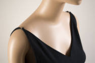 Detail view of black V-neck bathing suit with tapered shoulder straps secured with brass clasp