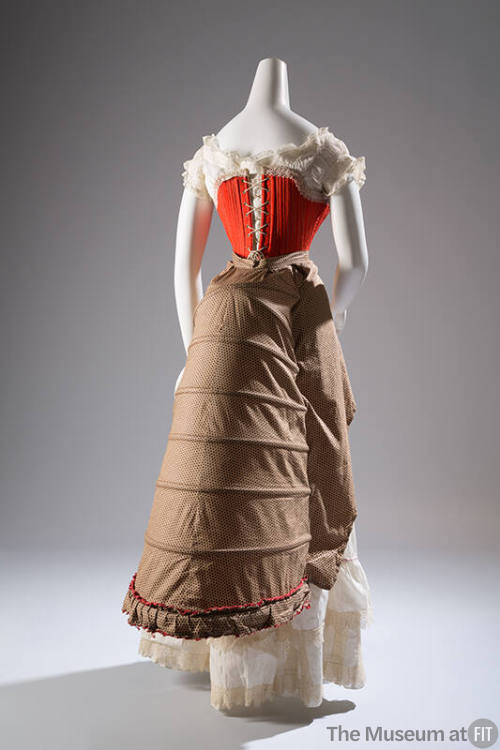 Back view of red laced corset over white lace top; with brown 6-tier bustle and white petticoat