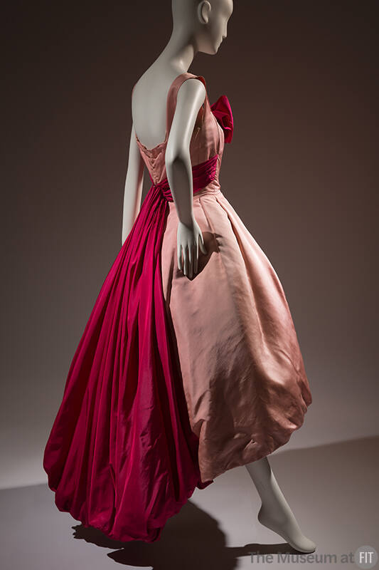 Back view of pink sleeveless evening dress with dark pink sash around waist extending down back…