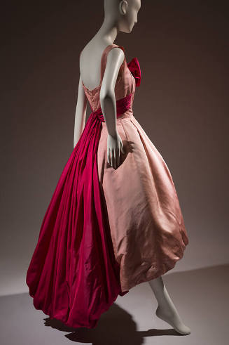 Back view of pink sleeveless evening dress with dark pink sash around waist extending down back…