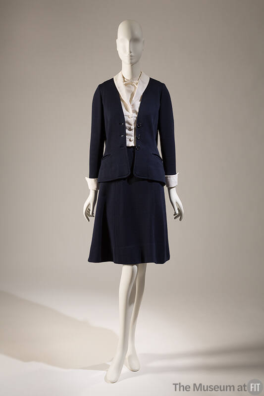 Navy blue suit with cardigan style jacket and matching A-line knee length skirt; dressed with w…