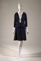 Navy blue suit with cardigan style jacket and matching A-line knee length skirt; dressed with w…