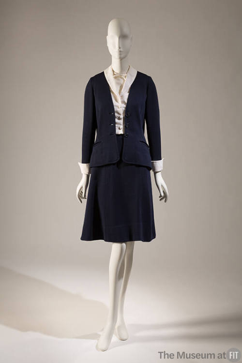 Navy blue suit with cardigan style jacket and matching A-line knee length skirt; dressed with w…