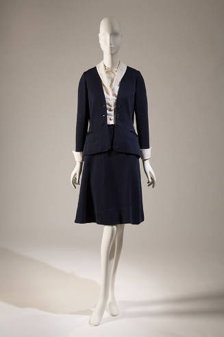 Navy blue suit with cardigan style jacket and matching A-line knee length skirt; dressed with w…