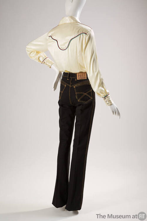 Back view of black four pocket jeans styled with white long-sleeved button down