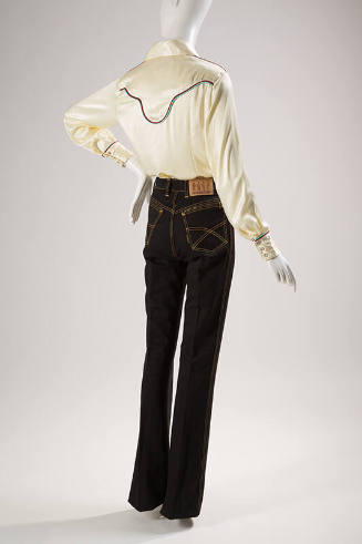 Back view of black four pocket jeans styled with white long-sleeved button down