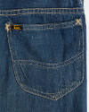 Detail view of blue jeans showing back pocket with Lee logo tag and stitching