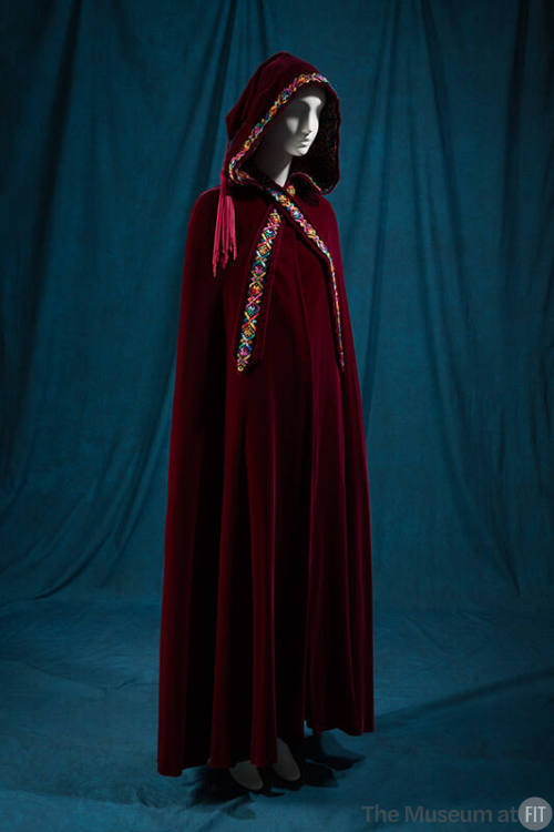 Red floor length hooded cape with multicolor embroidered trim, tassel hanging from hood