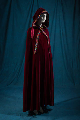 Red floor length hooded cape with multicolor embroidered trim, tassel hanging from hood