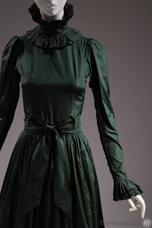 Detail of green taffeta gown with high ruffle neck, long sleeve with ruffle cuff, gathered skir…