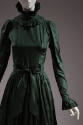 Detail of green taffeta gown with high ruffle neck, long sleeve with ruffle cuff, gathered skir…