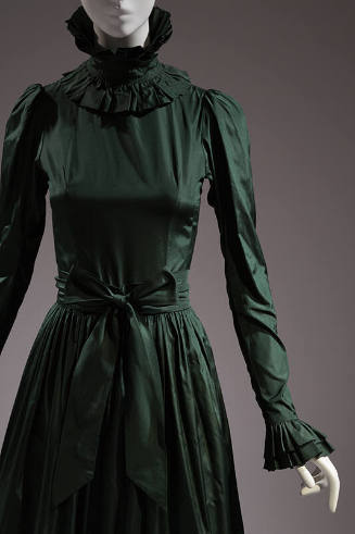 Detail of green taffeta gown with high ruffle neck, long sleeve with ruffle cuff, gathered skir…