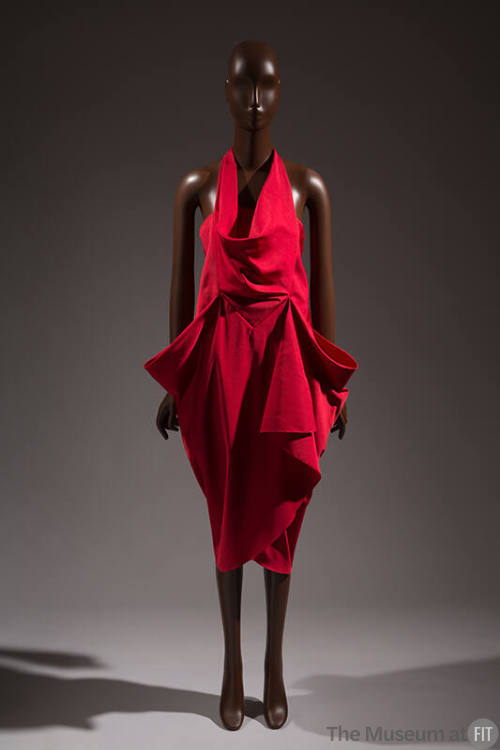 Sleeveless red dress with cowl front halter bib over strapless bodice; calf length wrap skirt w…
