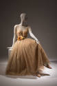Sheer gold dress with short sleeve bodice over slip with full skirt, large flower at waist cumm…