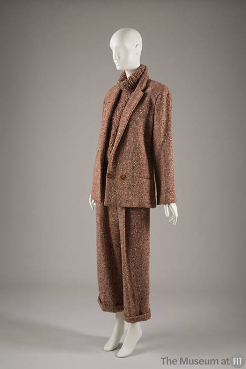Light brown nubby tweed suit jacket over turtleneck cableknit sweater and matching cuffed pants…