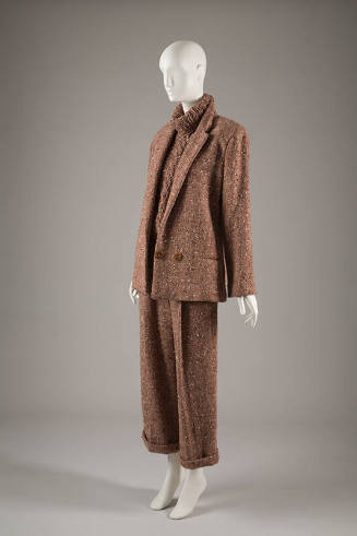 Light brown nubby tweed suit jacket over turtleneck cableknit sweater and matching cuffed pants…