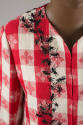 Detail of red and white tablecloth jacket shoulder with embroidered black ants
