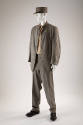 Man’s grey prison uniform of button front stand collar jacket, matching pants, flat top hat wit…