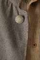 Detail view of prison uniform jacket button reading “State Prison” and brown and white striped …